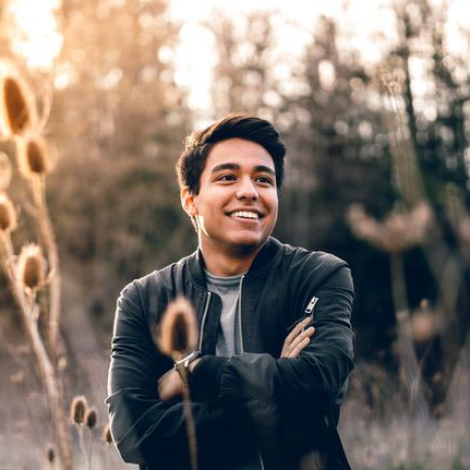 asian man posing for the picture in a field